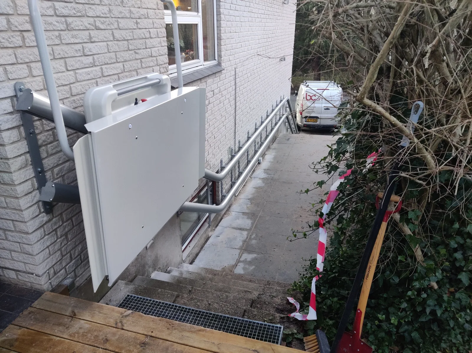 Plateaulift bochtige trap aan oranje gepleisterd pand — Internal Drive rail volgt trap-geometrie